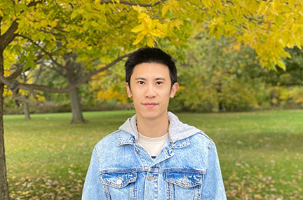Chen Wang in front of fall-colored trees